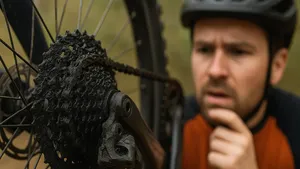 Wielrenner kijkt bezorgd naar vuile fietsketting en cassette door te veel smeren