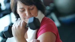Fitte vrouw van middelbare leeftijd doet krachttraining met een dumbbell voor een stevigere huid.
