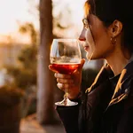 Young woman with a glass of red wine in sunset light at a terrace.