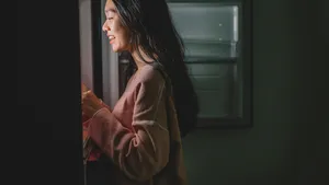 an asian chinese female looking for food from the refrigerator during mid night in the kitchen holding a plate