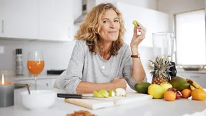 Shot of a woman preparing and eating fruit before making a smoothie