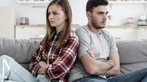 Young couple experiencing problems in relations sitting next to each other but unwilling to communicate