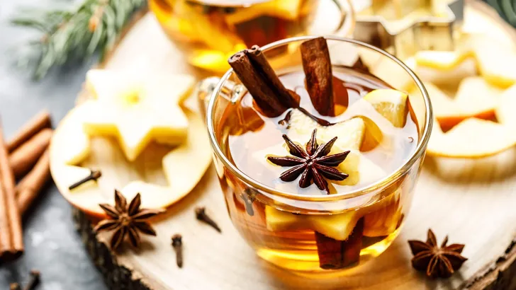 Hot drink for New Year, Christmas or autumn holidays. Mulled cider or spiced tea or mulled white wine with lemon, apples, cinnamon, anise, cloves.