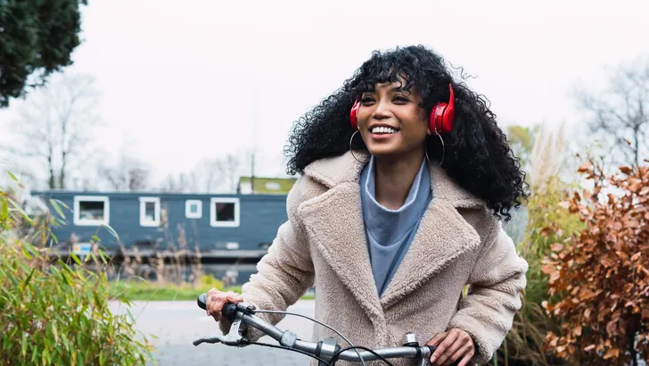 Smiling stylish woman listening to music outdoors in city.