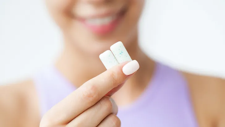 Een vrouw houdt twee stukjes kauwgom dicht bij de camera.