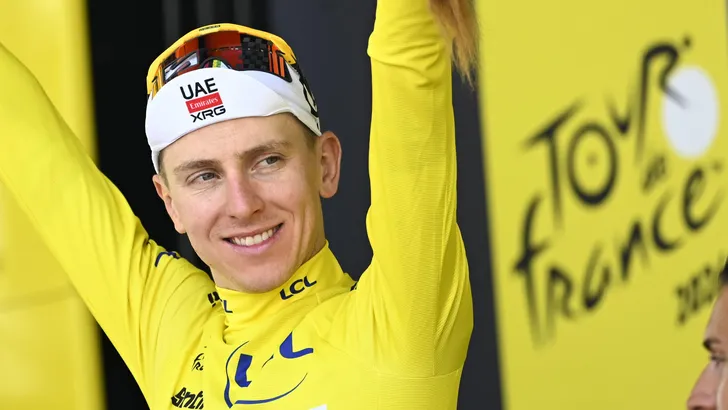 Lachende Tadej Pogačar in de gele trui op het podium van de Tour de France.