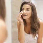 Beautiful brunette woman removing makeup from her face