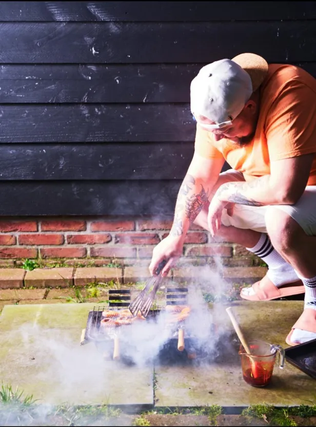 Tv-kok Nick Toet buiten aan het barbecueën op een kleine barbecue. 