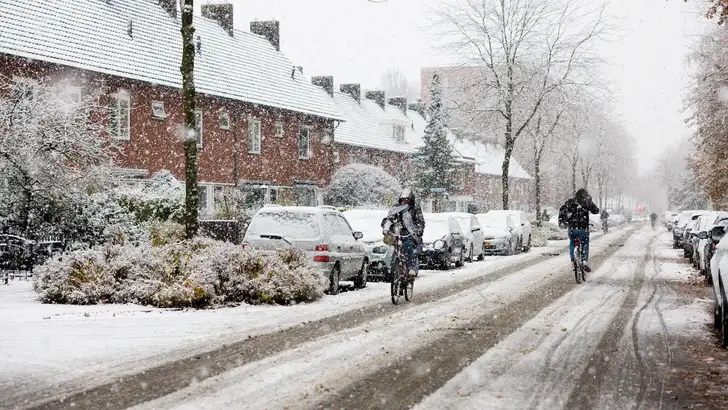 Fietser trotseren sneeuw in woonwijk van winter 2026 in Tilburg.