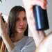 Vrouw spuit droogshampoo in haar haar voor een frisse look.