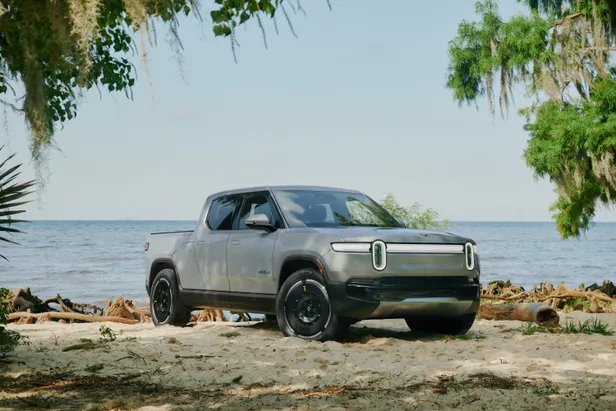 Rivian R1T pick-up truck op een strand