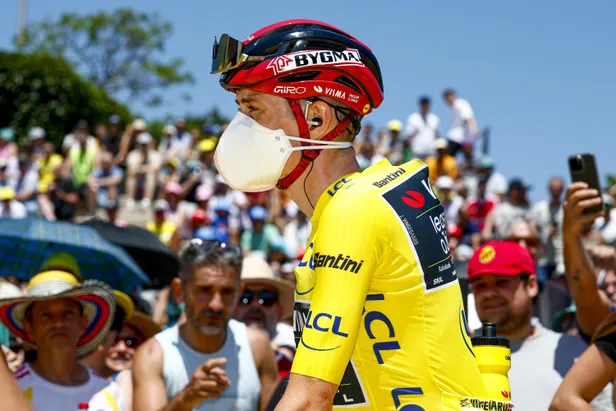 Jonas Vingegaard in de gele trui met een mondkapje op tijdens de Tour de France.