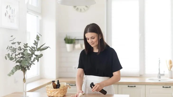 Young woman cleans the kitchen with eco products.