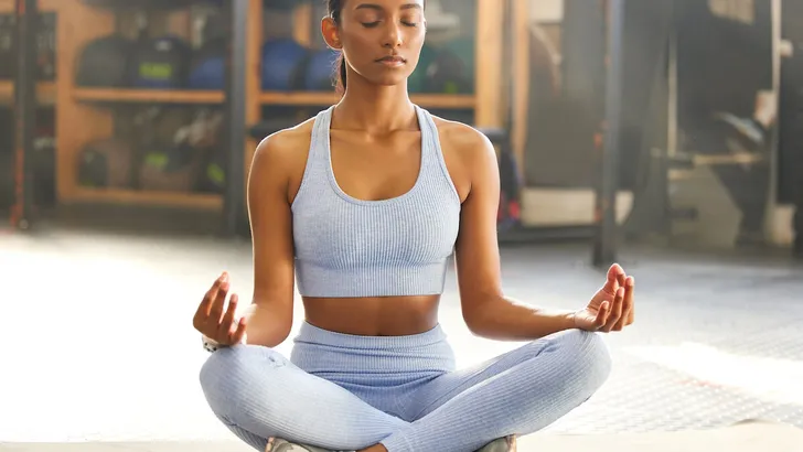 Yoga, meditation and Indian woman for wellness, mindfulness and breathing exercise on gym floor. Mental health, meditate and female person in lotus pose for calm mindset, zen and balance in training