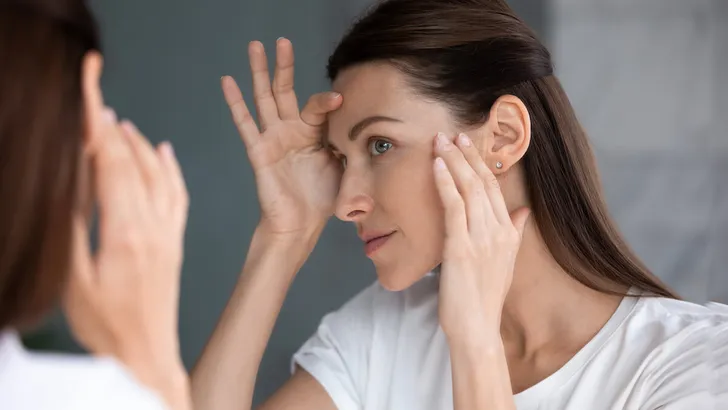 Satisfied woman looking in mirror check face after beauty treatment