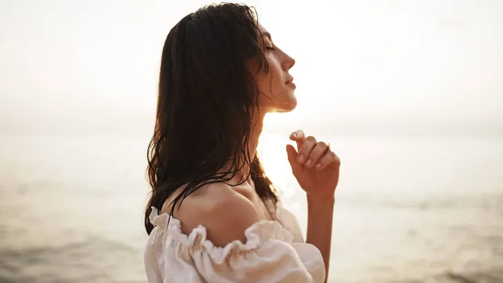Portrait of young brunette haired woman at the beach at sunset