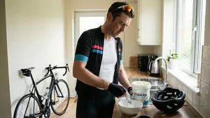 Wielrenner in fietskleding schept kwark uit een grote verpakking in een kom in de keuken na een training.
