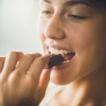 Close up of a happy woman eating chocolate.