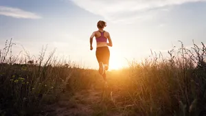 Young sporty girl running on a rural road at sunset