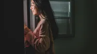 an asian chinese female looking for food from the refrigerator during mid night in the kitchen holding a plate