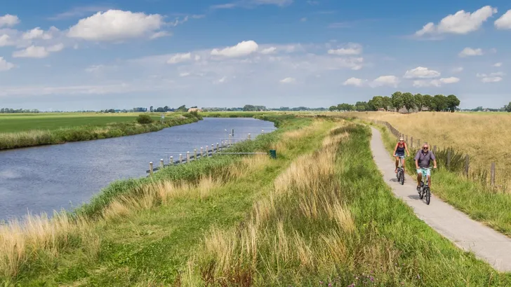 Panorama of a couple riding their bicycle along the Reitdiep river in Groningen, Holland