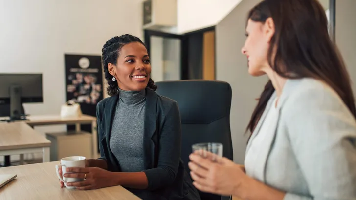 Positive female coworkers talking while working together.