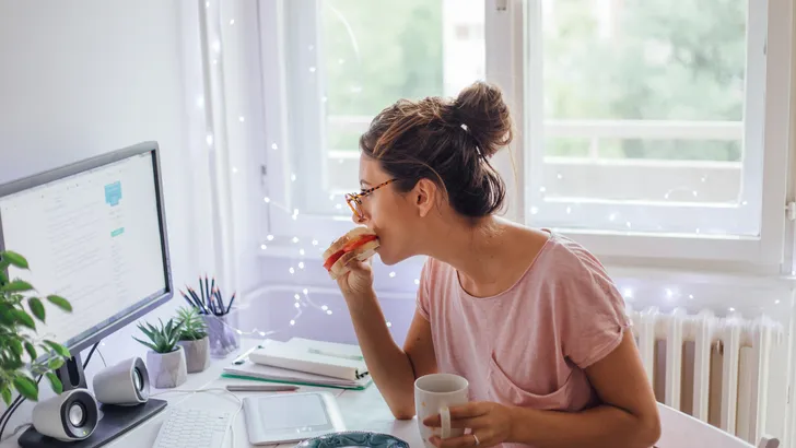 Vrouw aan het eten achter haar bureau