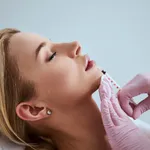 Professional cosmetologist injecting a dermal filler into the patient lips