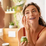 Woman applying moisturiser on face during morning routine