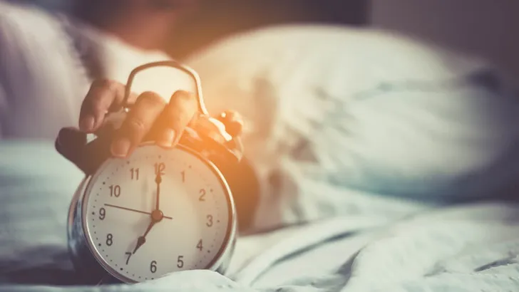 Clock on the bed in the morning.