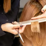 Hairdresser cuts hair to young woman