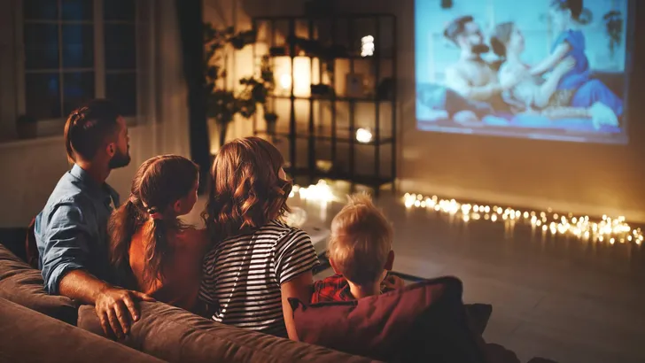 family mother father and children watching projector, TV, movies with popcorn in   evening   at home