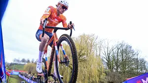 ereldkampioen veldrijden Mathieu van der Poel met een geconcentreerde blik en duidelijke modderspatten op zijn gezicht en regenboogtrui tijdens het WK in Hulst.