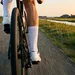 Wielrenner met witte fietssokken en schoenen in actie op een Nederlandse polderweg.