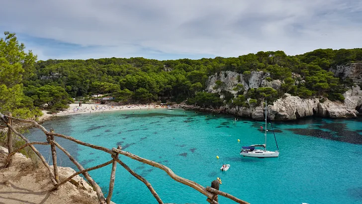 Foto van een strand met helderblauwe zee op het Spaanse eiland Menorca.