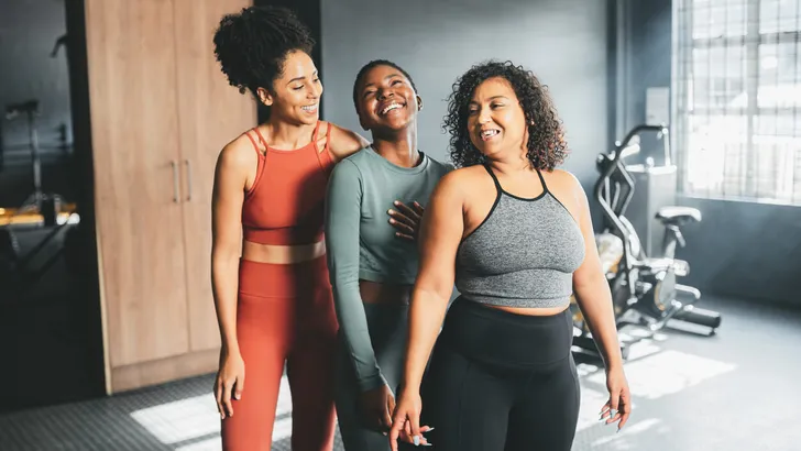 Group exercise of black women training in gym or workout area for wellness, health or fitness. Real, body positive or motivated female friends in gym laughing or conversation in sportswear.