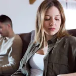 Angry young couple sitting on sofa together and looking to oppos