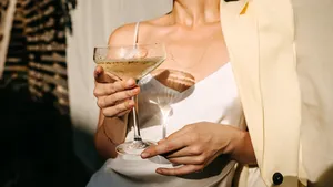 Beau Monde's tips voor het weekend. – Foto van vrouw in witte blazer met cocktail in hand.