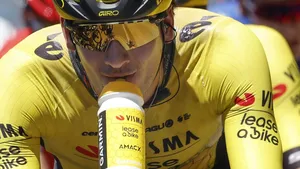 Close-up van een Visma-renner die tijdens het fietsen uit een bidon drinkt, met focus op gezicht en bidon.