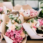 A lot of flower bouquets at the florist shop on the table made of hydrangea, roses, peonies, eustoma in pink and sea green colors