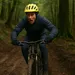 Mountainbiker in winterkleding rijdt gespannen een modderige afdaling af en verliest bijna de controle op een smal bosparcours.