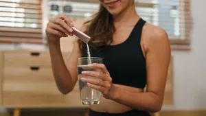 vrouw doet supplement in drankje