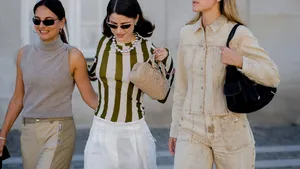 Drie meiden tijdens fashion week. Middelste draagt een witte linnen broek