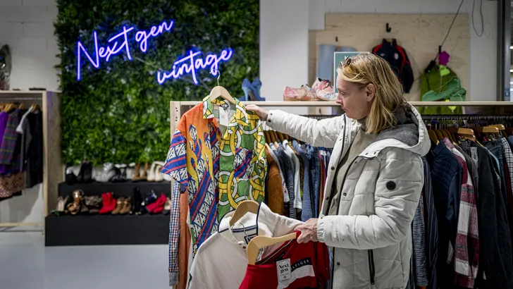 Vrouw zoekt naar tweedehands items in shop-in-shop, vintage kleding van topkwaliteit.