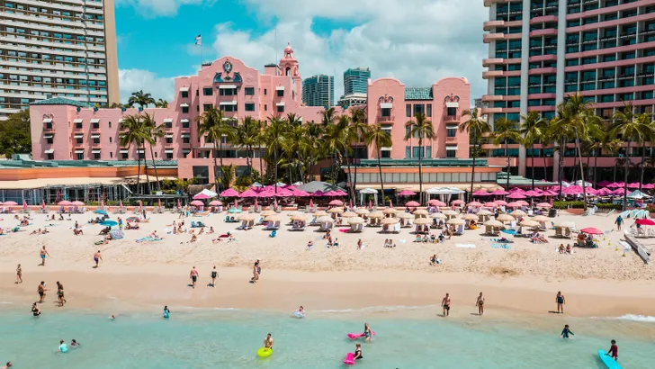 Foto van Royal Hawaiian Resort, een roze hotel aan de kust van Waikiki.