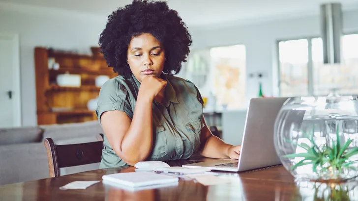 Woman looking concerned while paying bills from home