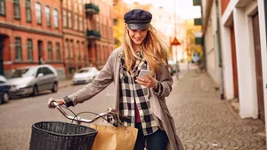 Young woman using a smartphone while pushing her bicycle in the city