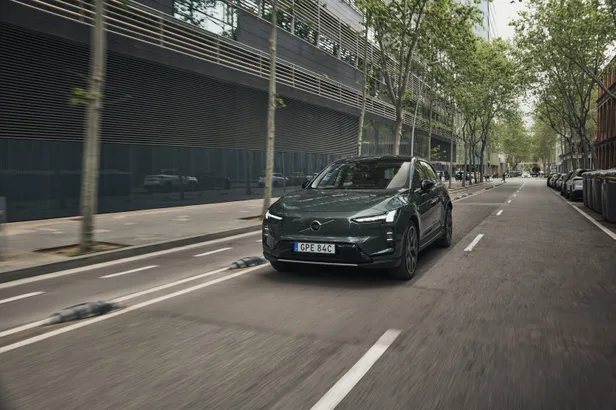 Groene Volvo EX60 rijdt door een stedelijke straat