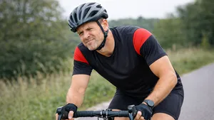 Man op een racefiets met gespannen blik tijdens het fietsen op een landelijke weg.