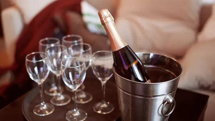 Zilverkleurige RVS wijnkoeler gevuld met ijs en een fles op een kersttafel, de goedkope Action-dupe van dure designmerken.